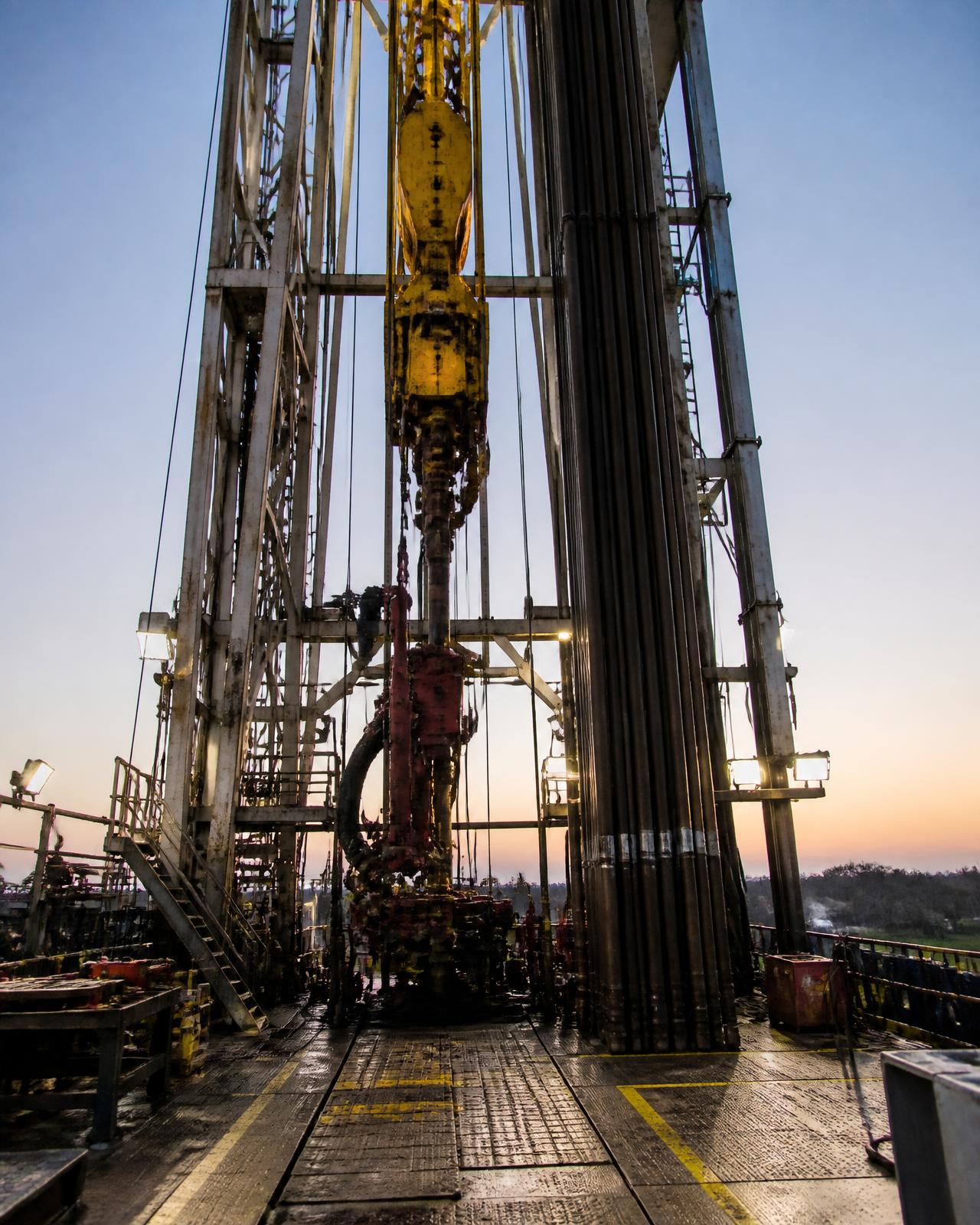 Drilling rig derrick with top drive and drill floor at dusk