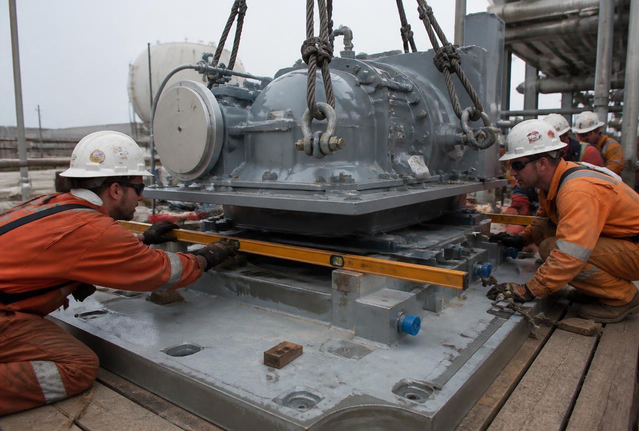 Engineers aligning heavy machinery onto a baseplate during installation